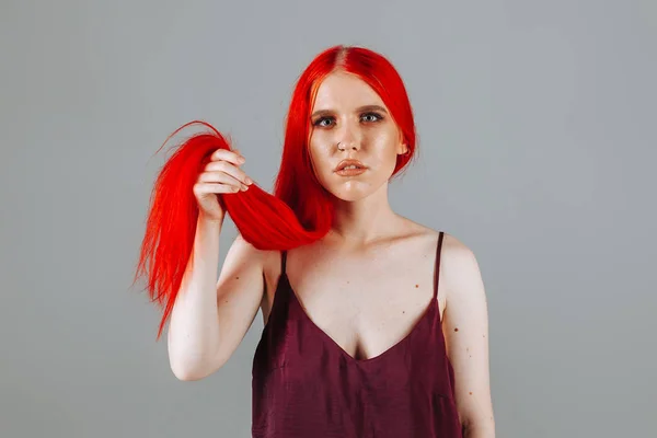 Girl touches her red long hair
