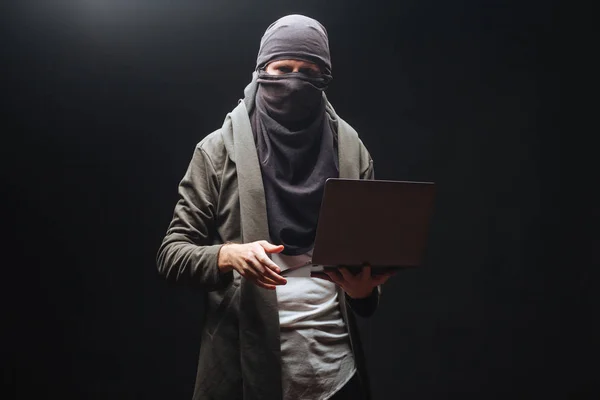 Terrorysta z laptopem na czarnym tle — Zdjęcie stockowe