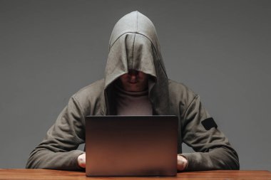 Karanlık bir arka plan üzerinde bir dizüstü bilgisayar ile bir kapüşonlu Hacker