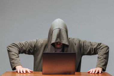 Karanlık bir arka plan üzerinde bir dizüstü bilgisayar ile bir kapüşonlu Hacker