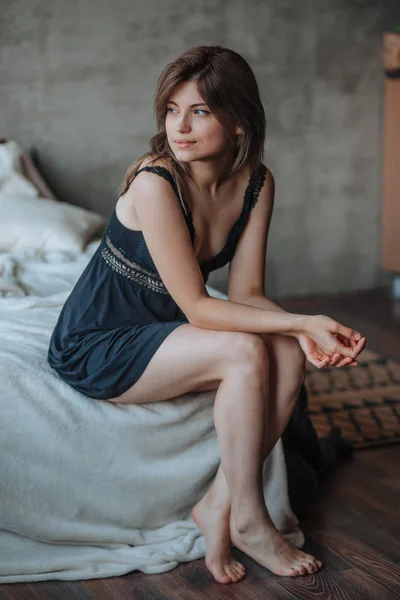 Девушка с красивыми ногами сидит на кровати — стоковое фото