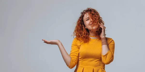 La chica pelirroja sostiene en la palma sobre un fondo gris claro — Foto de Stock