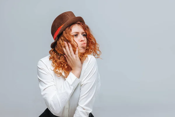The red-haired girl in a brown hat pulls lip kiss — Stock Photo, Image