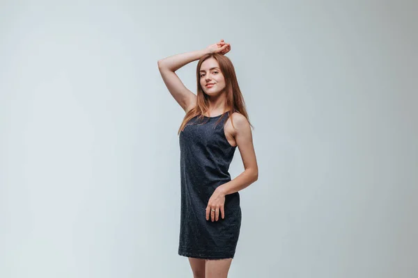Chica en un vestido oscuro posando sobre un fondo gris —  Fotos de Stock