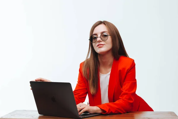 Sexy Mädchen in roter Jacke arbeitet am Computer an einem weißen Bac — Stockfoto