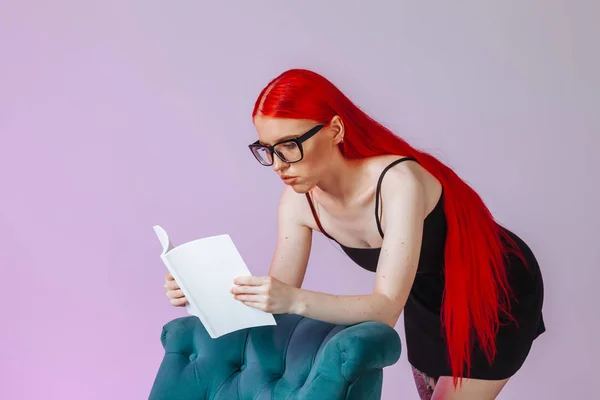 Dívka s červenými dlouhými vlasy, která čte bílou knihu na růžovém působivý — Stock fotografie