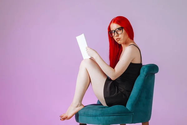 Girl with red long hair sitting on a chair and reading a book on — Stock Photo, Image