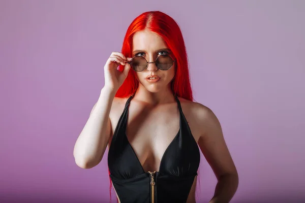 Retrato de uma menina com cabelo longo vermelho em óculos redondos em um rosa — Fotografia de Stock