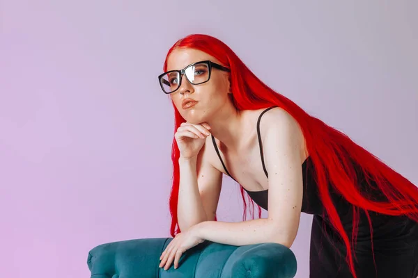 Retrato de una chica con el pelo largo rojo usando gafas en un rosa — Foto de Stock