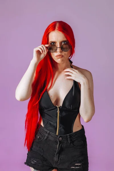 Retrato de una chica con el pelo largo rojo en gafas redondas en un rosa — Foto de Stock