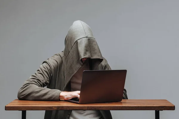 Hacker in Kapuze ohne Gesicht am Laptop — Stockbild Hacker in Kapuze ohne Gesicht am Laptop — Stockfoto