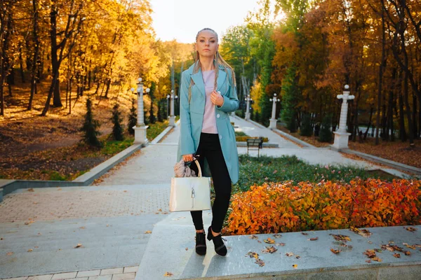 Flicka promenader i parken på hösten med en vit väska i en choklad — Stockfoto