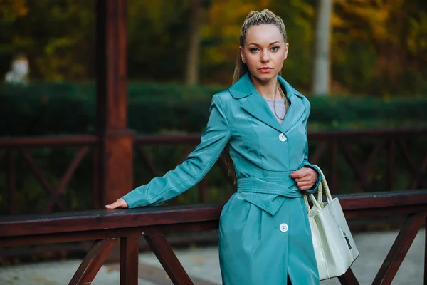 Una ragazza è in piedi con una borsa bianca nel parco autunnale — Foto Stock