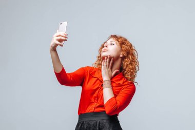 Kızıl saçlı kız açık gri sırt telefonda selfie alır