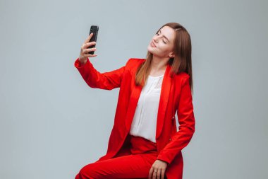 kırmızı ceketli kız gri bir backg telefonda bir selfie alır