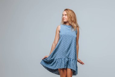 Kız açık gri arka plan üzerinde bezelye ile mavi bir elbise giyer