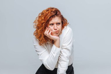 Kızıl saçlı kız gri bir arka plan üzerinde memnun