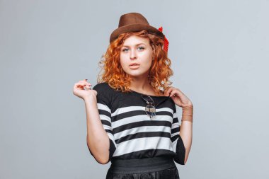 gri bir arka plan üzerinde bir şapka poz kırmızı saçlı kız