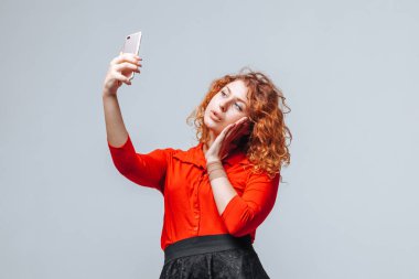 Kızıl saçlı kız açık gri sırt telefonda selfie alır