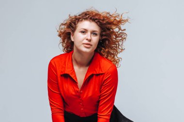 Gri arka plan üzerinde kızıl saçlı gülümseyen bir kızın portresi