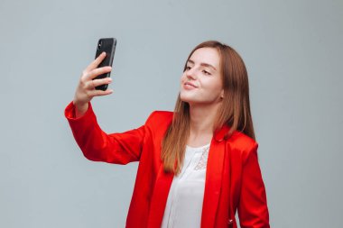 kırmızı ceketli kız gri bir backg telefonda bir selfie alır