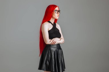 Gözlük ve deri etek posi giyen kırmızı uzun saçlı kız
