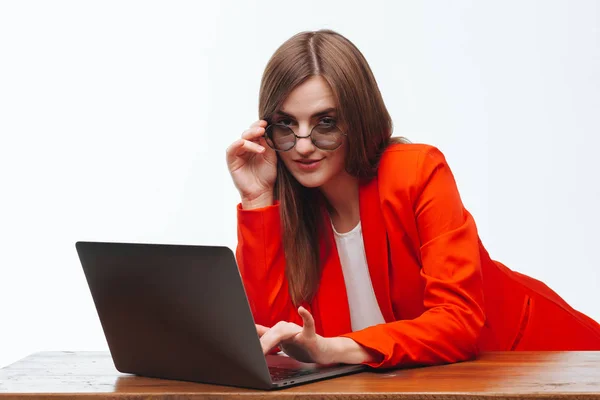 Sexy girl in a red jacket working at the computer on a white bac — Stock Photo, Image