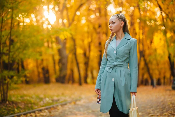 Menina andando no parque no outono com um saco branco em um cacau — Fotografia de Stock