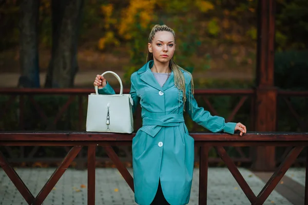 Дівчина стоїть з білою сумкою в осінньому парку — стокове фото