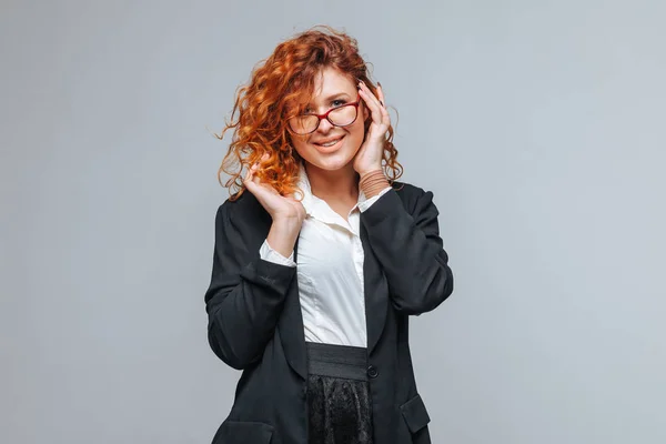 Vöröshajú nő egy öltönyt, és megérinti szemüveg — Stock Fotó