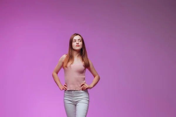 Дівчина кладе руки на стегна на рожевий фон — стокове фото