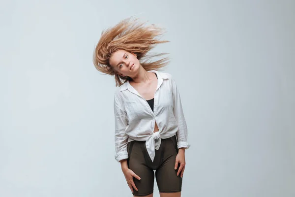 Chica sacude su cabello sobre un fondo gris —  Fotos de Stock
