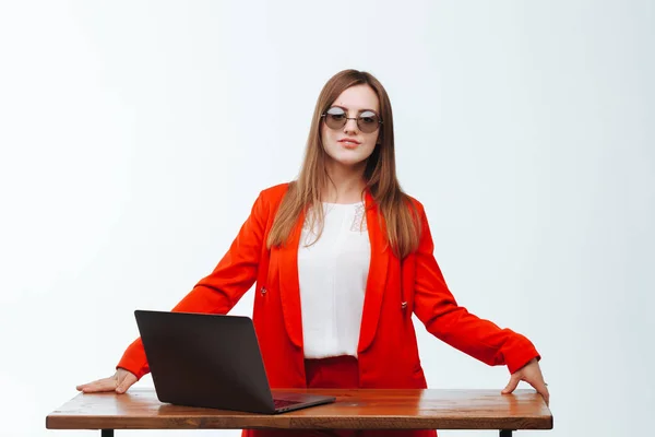 Sexy Mädchen in roter Jacke arbeitet am Computer an einem weißen Bac — Stockfoto