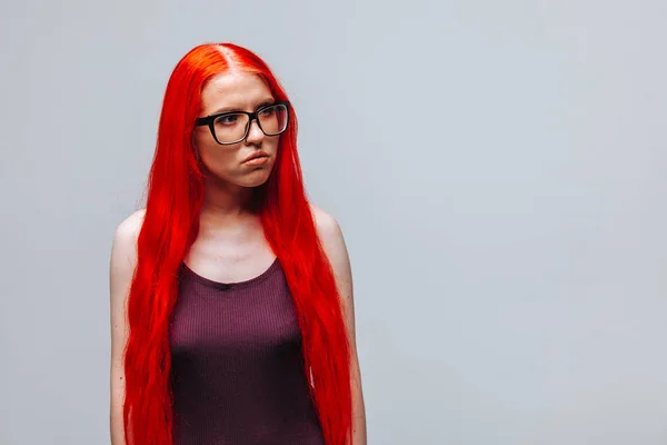 Ragazza con i capelli lunghi rossi che indossa occhiali su un backgrou grigio chiaro — Foto Stock