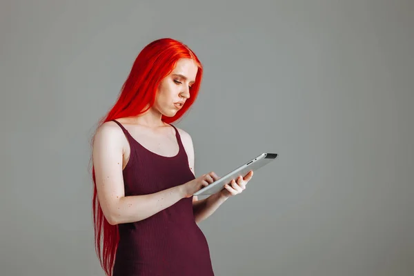 Menina com cabelo longo vermelho procurando tablet — Fotografia de Stock