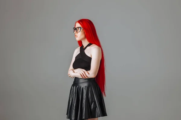 Girl with red long hair wearing glasses and a leather skirt posi — Stock Photo, Image