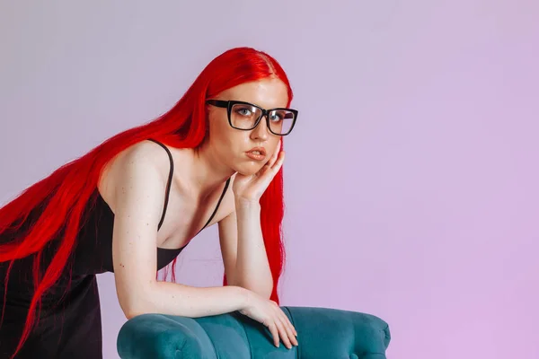 Retrato de una chica con el pelo largo rojo usando gafas en un rosa —  Fotos de Stock