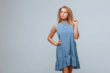 Kız açık gri arka plan üzerinde bezelye ile mavi bir elbise giyer