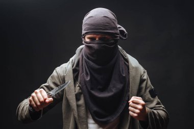 bir maskeli suçlu bir bıçak ile karanlık arka plan tehdit
