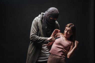Maskeli suçlu bıçaklı kızı tehdit ediyor, karanlık arka plan