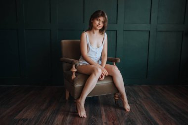 Uzun ince bacakları ile güzel kız karanlık bir sandalyede oturan 