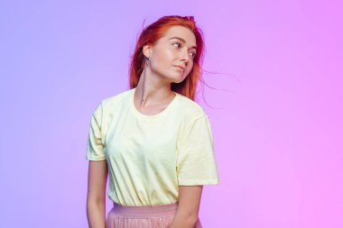 Renkli arka planda poz veren kızıl saçlı kız.