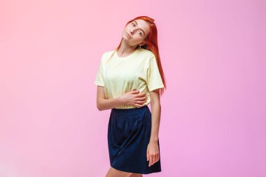 Pembe arka planda poz veren kızıl saçlı kız