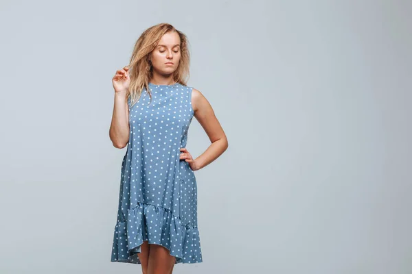 La chica lleva un vestido azul con guisantes sobre un fondo gris claro —  Fotos de Stock