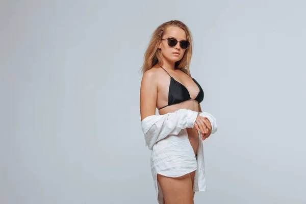 Chica en un traje de baño negro y gafas de sol y una camisa blanca en una l —  Fotos de Stock