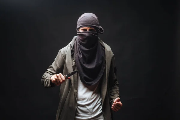 Przestępca w masce grozi nożem na ciemnym tle — Zdjęcie stockowe