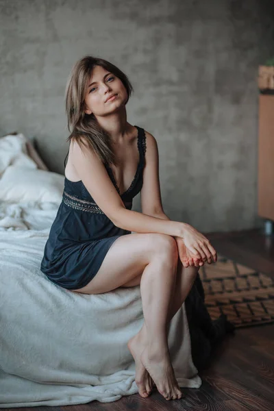 Menina com belas pernas sentadas na cama — Fotografia de Stock
