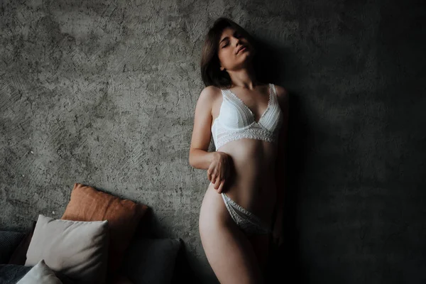 Seksowna dziewczyna zabiera białą bieliznę na ciemnym tle — Zdjęcie stockowe