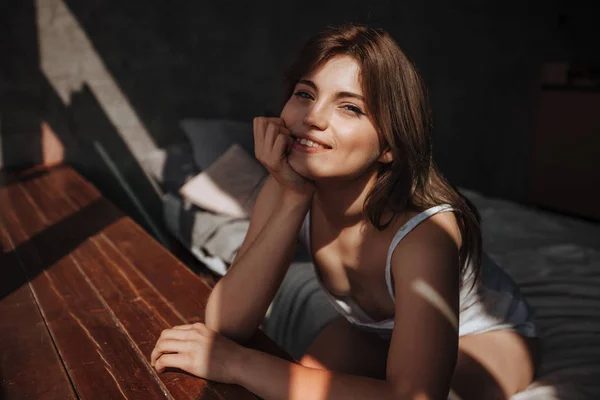 Portret van een schattig meisje in de ochtend door het raam op het bed — Stockfoto