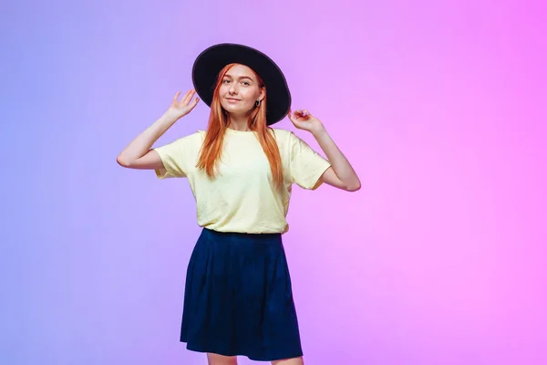 Pelirroja chica en sombrero toca en un fondo de color —  Fotos de Stock